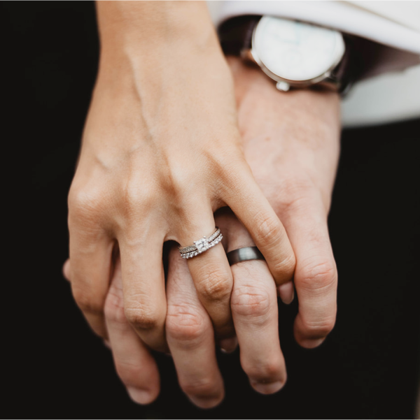Couple holding hands showing off their wedding rings.