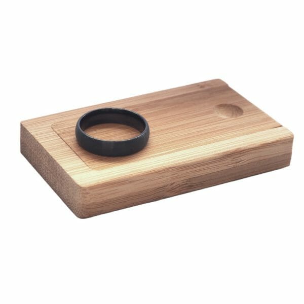 Black wedding ring in a wooden ring box on white background.