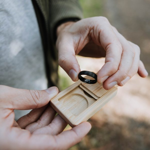 Man getting black wedding ring out of wooden box
